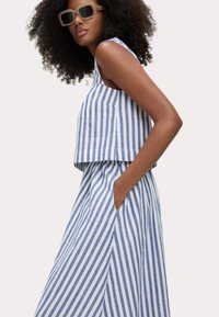 Gestreepte blauwe en witte tweedelige set met een mouwloze top en een lange rok met zakken, gemaakt van een lichtgewicht stof.