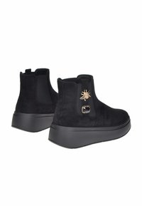 Stivaletti neri in suede con suole spesse, pannelli laterali elastici e decorazioni in oro a forma di ape e gemme nere.