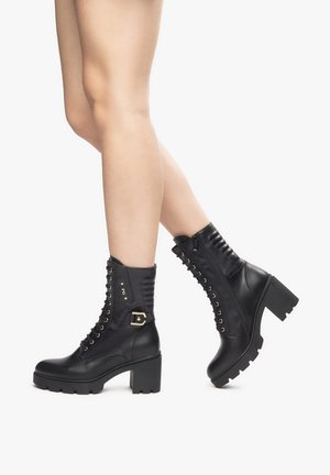 Black leather ankle boots feature a lace-up design with gold-toned eyelets, side zipper, and a chunky block heel. Textured back panel.