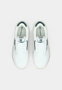 Ζευγάρι λευκά αθλητικά παπούτσια Champion με μαύρες λεπτομέρειες, δεμένα με κορδόνια, σε θέα από πάνω σε ανοιχτό γκρι φόντο.