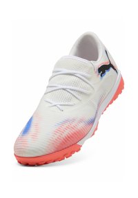 Zapatilla deportiva blanca con parte superior texturizada, que presenta patrones en degradé azul y rosa. Suela rosa con pequeños tacos de tracción y cordones blancos.