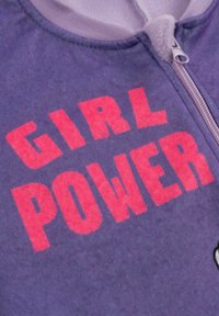 Tessuto viola con una cerniera e una stampa audace in lettere maiuscole "GIRL POWER" di colore rosa.
