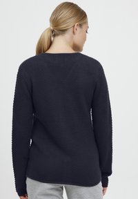 Black knitted sweater with a textured pattern, featuring long sleeves and a round neckline, viewed from the back.