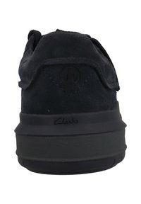 Schwarze Wildleder-Sneaker mit gepolstertem Kragen, schwarzer Gummisohle und geprägtem Logo auf der Rückseite. Minimalistisches Design ohne sichtbare Akzente.