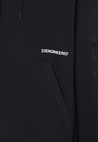 Svart sweatshirt med känguruficka, utrustad med en dragkedjeficka på sidan och vit "23ENGINEERED"-logotyp broderad på bröstet.