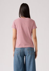 Rødt og hvitt stripete t-skjorte med korte ermer, rund halslinning, myk bomullsstoff, brukt sammen med løst sittende blå jeans med synlig bak søm.