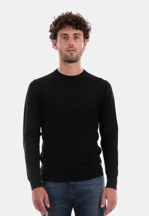 Maglione nero a maniche lunghe, lavorato a maglia, con scollatura a girocollo, design aderente, polsini a costine e una texture liscia, indossato su jeans di denim.