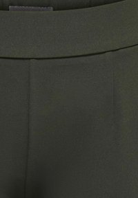 Pantalon vert foncé sur mesure avec une ceinture et un pli devant, fabriqué en tissu lisse.
