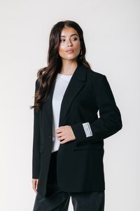 Must mustriga mustriga bleiser, mis on valmistatud siledast kangast, ühe nööbi sulgemisega, sakiliste kraede ja mansetil oleva etiketiga. Kantud valge särk.