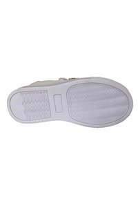 Suola di sneaker bianca con scanalature strutturate e un pannello centrale liscio. Il tallone presenta un logo inciso in modo sottile e un bordo leggermente rialzato.