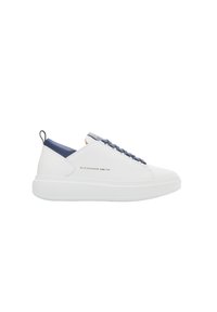 Sneaker bianca in pelle con accento blu navy sul tallone, caratterizzata da un marchio dorato, lacci rotondi e una suola bianca spessa.