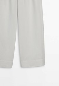 Pantalon gris clair à jambes droites avec un ourlet net, présenté de mi-cuisse vers le bas sur un fond blanc.