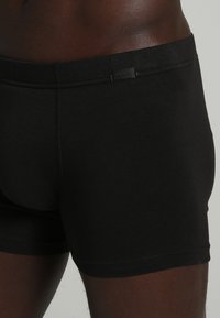 Svarta bomullshorts med en mjuk textur, som har en diskret etikett på midjebandet. Passformen är åtsittande och kroppsnära.