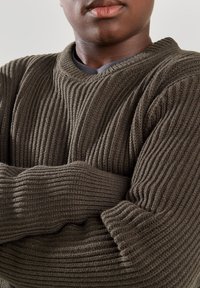 Strickpullover in dunkelorange-grün mit gerippter Textur, breiten Manschetten und V-Ausschnitt, aus einem dicken, gemütlichen Material gefertigt.