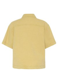 Vue arrière d'une chemise en denim beige à manches courtes, coupe carrée, avec un col et des détails de coutures visibles.