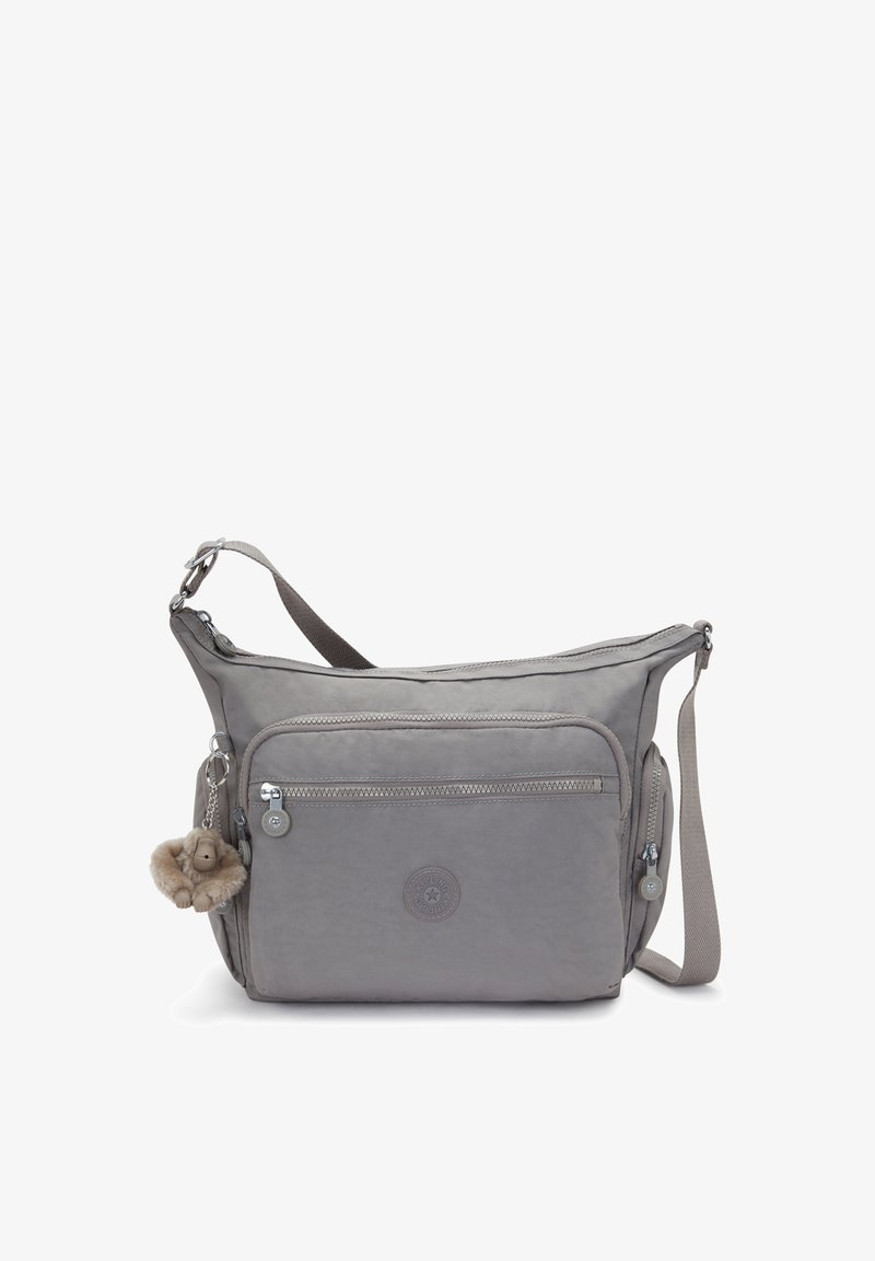 Szara torba na ramię z tkaniny, z zamykaną na zamek kieszenią z przodu, regulowanym paskiem oraz puszystym brelokiem z kluczykami. Ikoniczne logo wytłoczone z przodu.