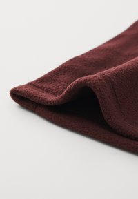 Bordeaux fleece-stoff, myk tekstur, litt bølget kant, viser en fyldig overflate med en glatt finish. Ingen mønstre eller utstyr synlig.