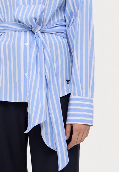 Lichtblauw gestreept shirt met een knoop in de taille, knoopsluiting aan de voorkant en verlengde mouwen met contrasterende witte strepen.