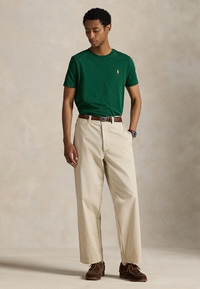 Πράσινο βαμβακερό μπλουζάκι με στρογγυλή λαιμόκοψη, μπεζ βαμβακερό παντελόνι, καφέ δερμάτινη ζώνη και καφέ παπούτσια τύπου boat. Απλός και κλασικός σχεδιασμός.