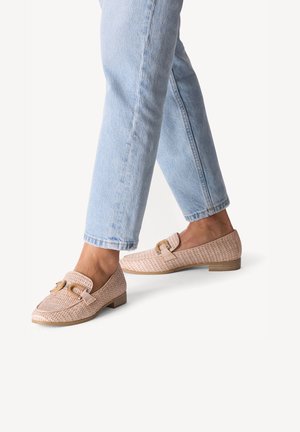 Chaussures plates tressées roses avec un petit talon, dotées d'une accent de sangle et d'une finition texturée, associées à un jean bleu clair retroussé.