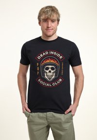 Camiseta de algodón negra con un gráfico central de un cráneo con un casco y llamas, rodeado del texto "SOCIAL CLUB MUERTO POR DENTRO".
