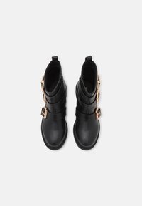 Czarne botki za kostkę o gładkim skórzanym wykończeniu, z trzema poziomymi paskami i złotymi klamrami. Solidne gumowe podeszwy i zapięcia na zamek.