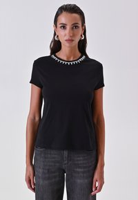 T-shirt nera a maniche corte con un colletto decorativo in strass. Tessuto morbido con una vestibilità comoda e design semplice. Abbinato a jeans scuri.