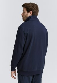 Felpa blu navy con colletto alto, polsini e orlo a coste, realizzata in un tessuto liscio e leggero. Design minimalista senza motivi.