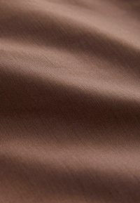 Tissu marron au toucher lisse et à l'éclat subtil, présentant de fines rayures diagonales qui créent une apparence élégante.