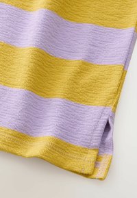 Primer plano de tela texturizada con rayas horizontales anchas en amarillo y lavanda y una pequeña abertura lateral en el dobladillo.