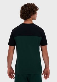Camiseta de manga corta para hombre con la parte superior negra y la parte inferior verde oscuro, fabricada en suave algodón, con un diseño clásico de cuello redondo.