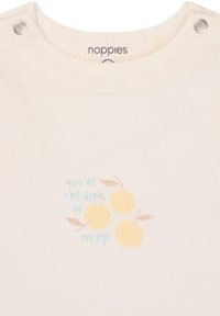 Kurzärmliges Shirt aus cremefarbener Baumwolle mit Druckknöpfen, das ein gelbes Obstmotiv und den Text "Du bist der Apfel meines Auges" zeigt.