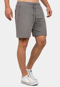 Pantaloni corti grigi realizzati in tessuto leggero, con cintura elastica e coulisse, tasche laterali e design slim fit.