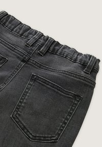 Pantalones de mezclilla negra con una cintura elástica fruncida. Cuenta con bolsillos traseros y costuras tonales. El material es texturizado y suave.