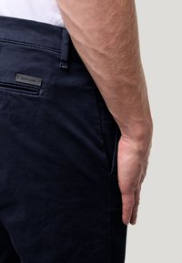 Navyblauwe katoenen broek met een gladde textuur. Voorzien van een achterzak en een klein metalen logo-label. Eenvoudig ontwerp met een aansluitende pasvorm.