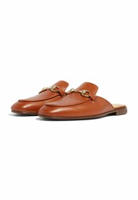 Mocasines de cuero marrón sin cordones con detalle de estribo dorado y tacón bajo apilado, angulados para mostrar las vistas superior y lateral.