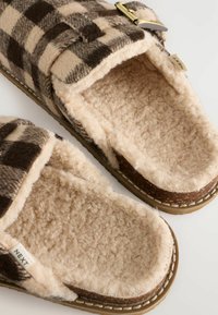 Brown and beige checked slippers with soft fleece lining, open toe design, and a gold buckle accent. Stitch detailing along the sole.