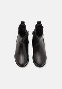 Bottes courtes en cuir noir à finition lisse, fermetures éclair de chaque côté, et bout arrondi. Doublure intérieure douce visible.