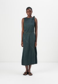 Denim dress with a sleeveless design, dark indigo color, asymmetrical seaming, and a knot detail on the left shoulder.