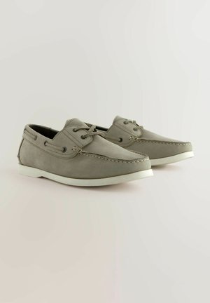 Zapatos de barco de cuero gris con suelas de goma blanca, punteras redondeadas, acentos de costura y diseño con cordones, con ojales laterales para ventilación.