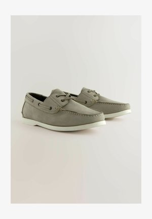 Pilkos odinės valtinės batai su baltais gumininiais kulnais, suapvalintais pirštais, siūlų akcentais ir raištelių dizainu, turintys šoninius oro angas vėdinimui.