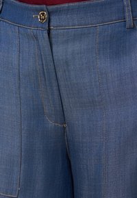 Pantaloni in denim caratterizzati da una tonalità blu, taglio dritto e chiusura frontale con bottone. Le cuciture e le tasche in evidenza arricchiscono il design complessivo.