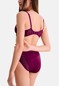 Bordeaux beha en hooggeknipte slipset met geometrische gaasaccenten, verstelbare banden en gladde stof voor een aansluitende silhouet.