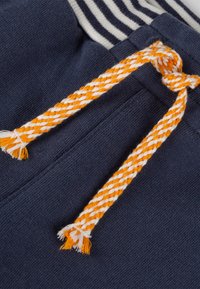 Navy Baumwollshorts mit einem weiß-blauen gestreiften Bund und einer orange-weißen geflochtenen Kordel mit Quasten.