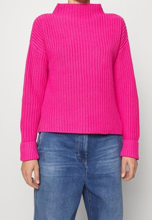 Helles rosa geripptes Sweatshirt mit hohem Kragen, weitem Ärmeln und umgeschlagenen Säumen. Kombiniert mit hellblauen Jeans, die einen lässigen Stil zeigen.