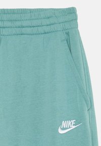 Zeleni bombažni jogger hlače z elastičnim pasom, stranskimi žepi in belim vezenim logotipom Nike. Mehka tekstura in sproščen dizajn.