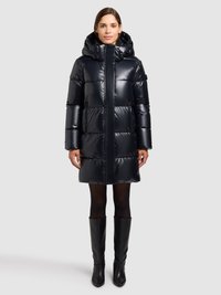 Čierny prešívaný kabát s kapucňou, s lesklým povrchom, kapucňovým dizajnom a vertikálnymi stehovými líniami. Nosený spolu s čižmami po kolená v čiernej farbe.