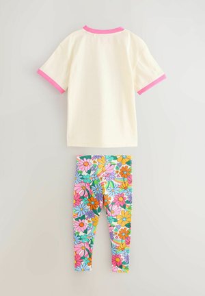 T-shirt med korte ærmer i cremefarve med en lyserød krave og manchetter, sammen med farverige leggings med et levende blomstermønster.