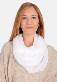 Écharpe blanche, légère, en plusieurs couches, faite d'un tissu doux et transparent. Elle est drapée autour du cou, mettant en valeur une texture lisse et un design fluide.