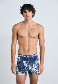 Boxer in jersey da uomo blu navy con un motivo di foglie tropicali bianche. Realizzati in tessuto morbido, presentano un elastico con logo in vita.